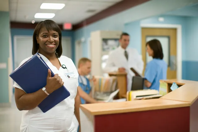 a doctor holding a file is smiling while other people are blurred in the background